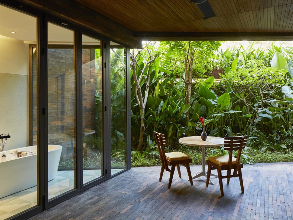 The Garden Suite at Potato Head Suites features an outdoor seating area beside a bathroom with clear windows.