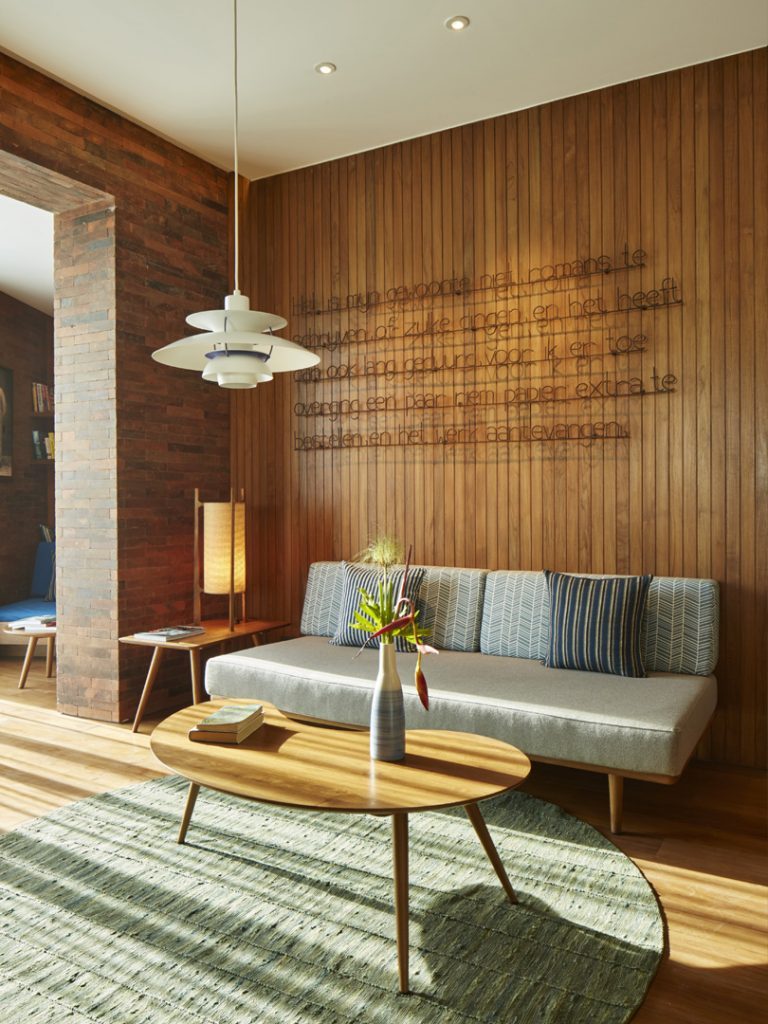 The living area of the Island Suite at Potato Head Suites in Seminyak features a wooden coffee table on a rug and a grey sofa.