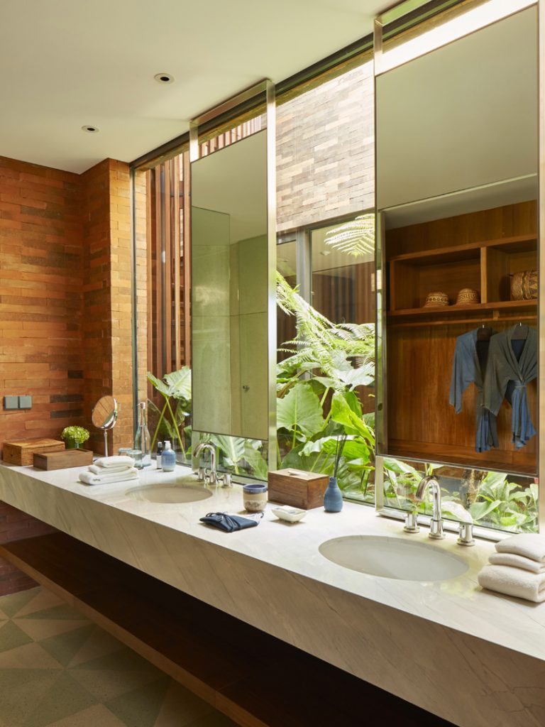 The bathroom in the Rooftop Suite at Potato Head Suites features a double sink and is decorated with plants.