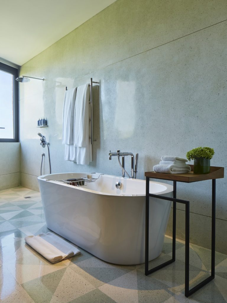 The bath area in the Rooftop Suite at Potato Head Suites in Seminyak, Bali features a shower as well as a bathtub.