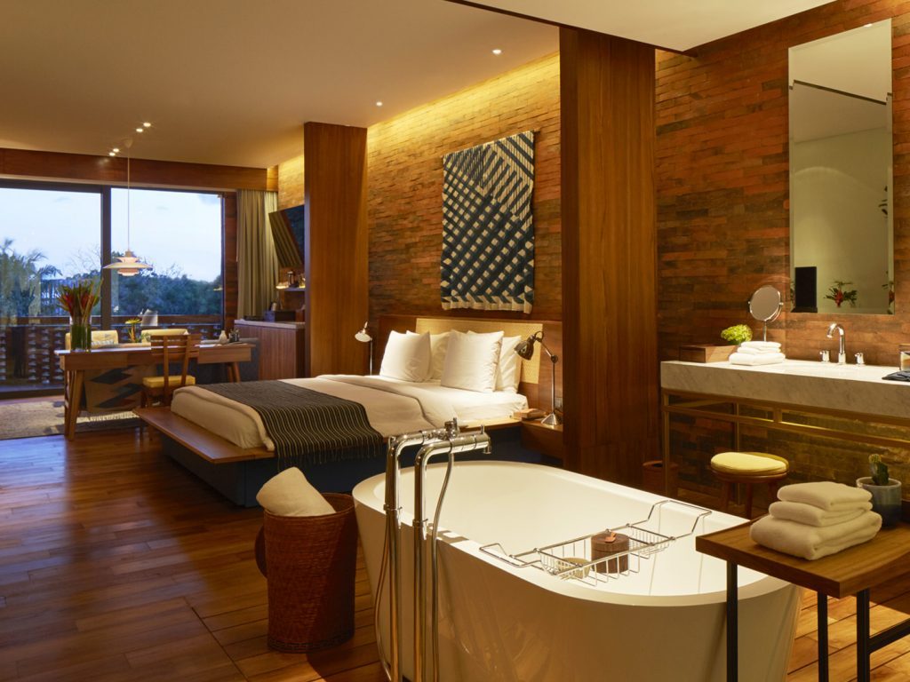 One of bedrooms of the Two Bedroom Suite at Potato Head Suites in Seminyak, Bali features a double bed and a bathtub.