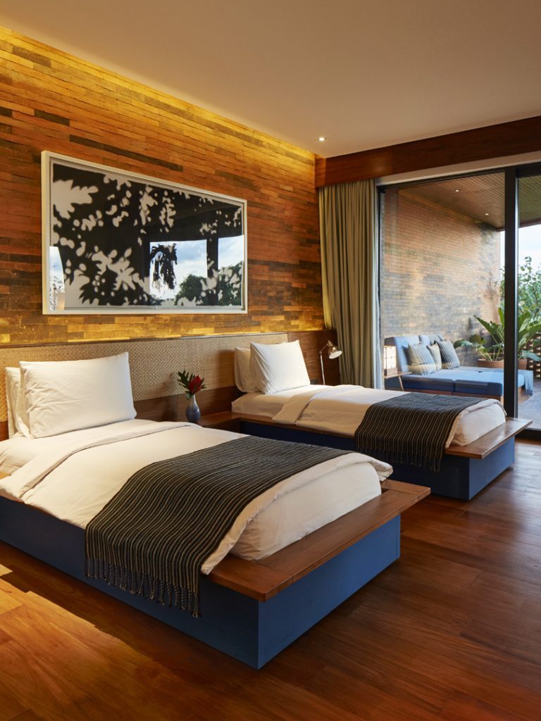 One of bedrooms of the Two Bedroom Suite at Potato Head Suites in Seminyak, Bali features twin beds and outdoor access.