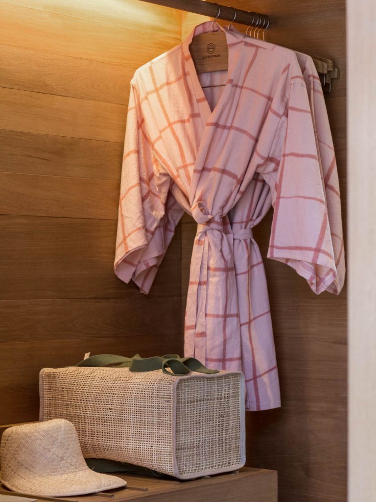 Pink bath robes hung on an open concept wardrobe in the studios at Potato Head Studios in Seminyak, Bali.