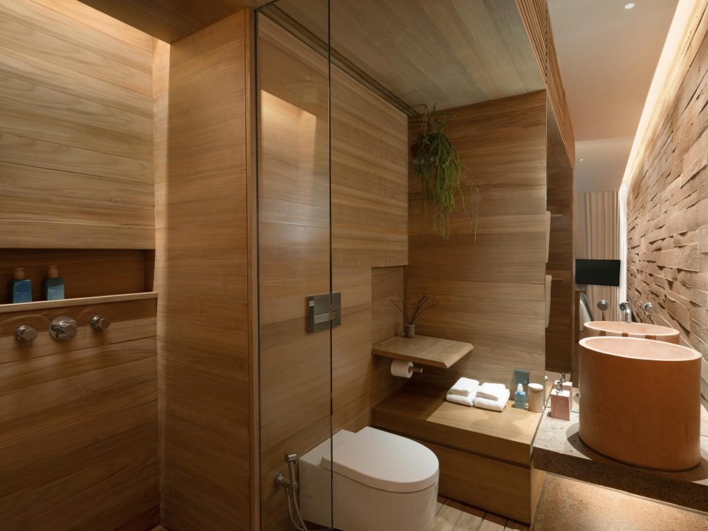 The wooden bathrooms at Potato Head Studios in Seminyak Bali features a shower, a sink and natural soaps.