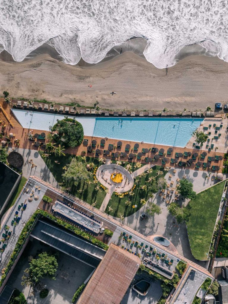 An aerial view of Potato Head Studios in Seminyak, Bali, showing part of the property, the pool as well as the beach.